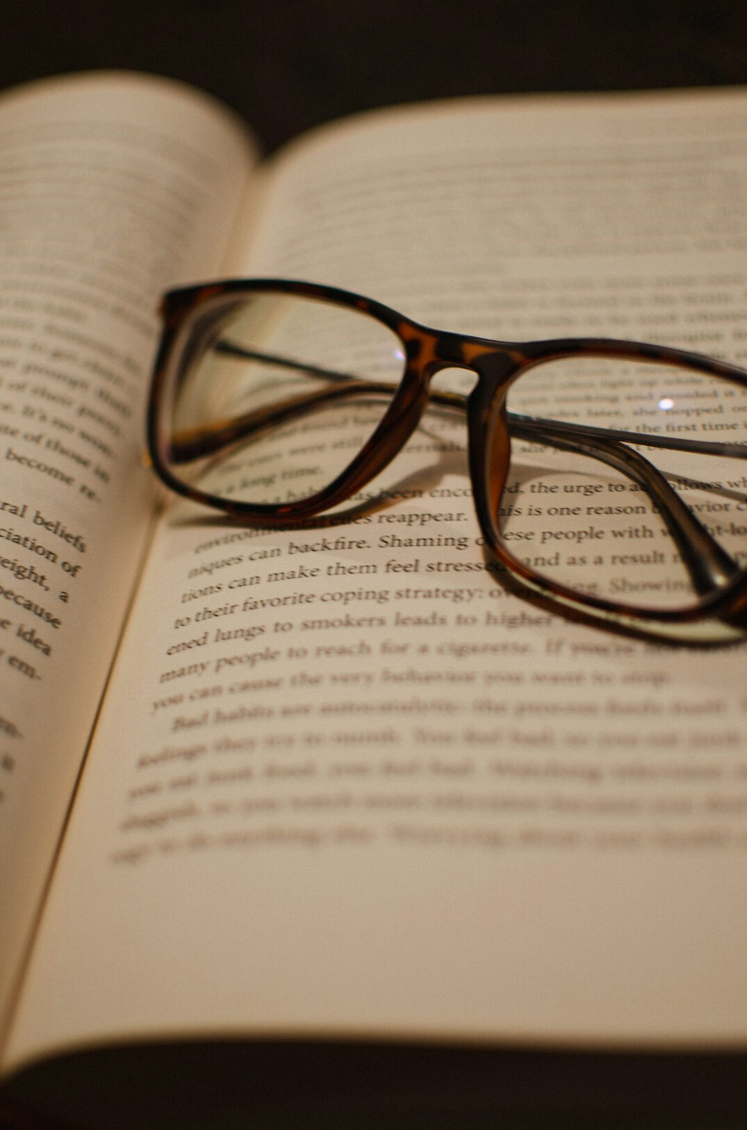 Open mystery novel on a wooden table with reading glasses