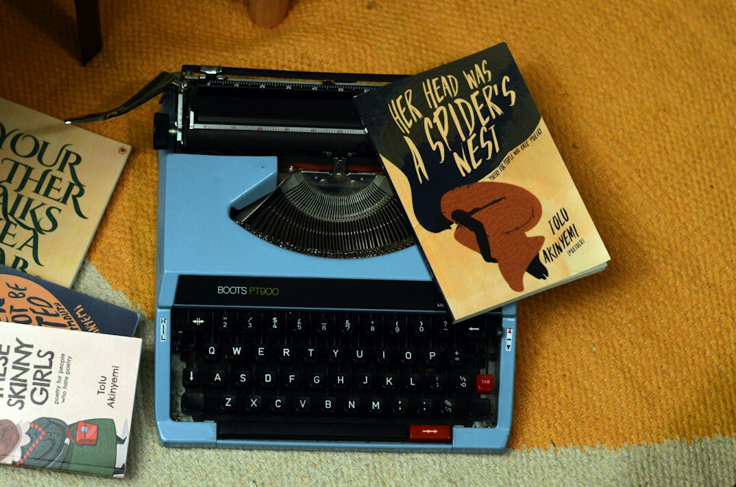 Stack of vintage books next to a manual typewriter on a desk