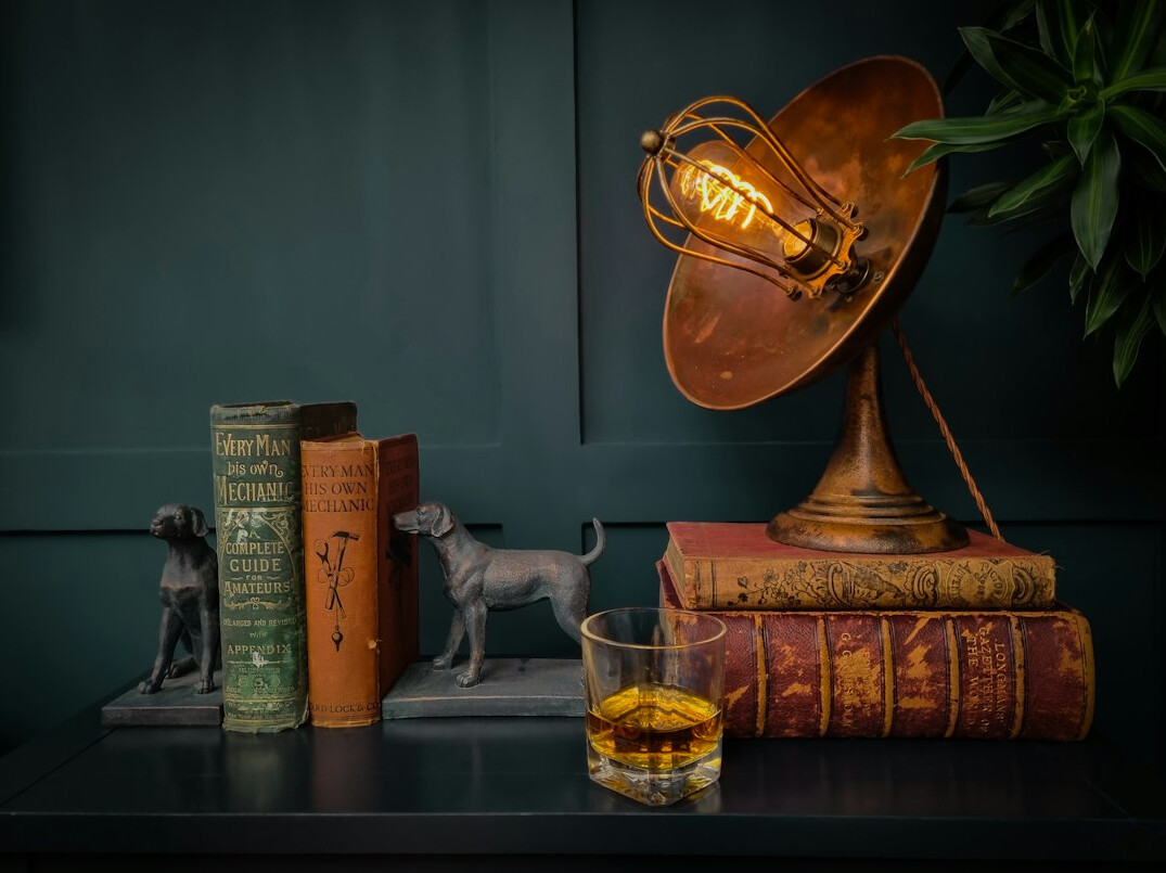 Stack of old hardcover books with a reading lamp on a desk